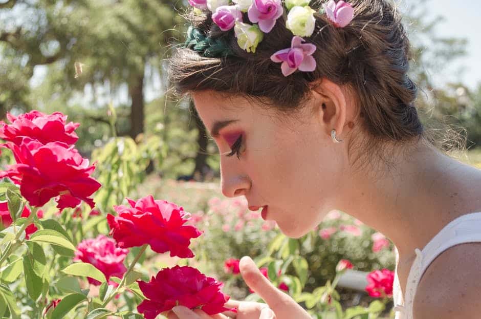 woman inhaling the fragrance of flowers in the garden